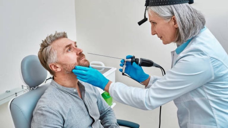 Diagnostic nasal endoscopy. Mature ENT doctor examining male patient nose using video ENT endoscope at medical clinic